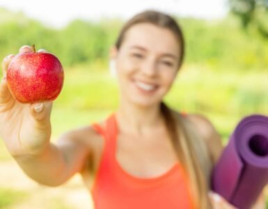 vrouw met apple en yogamat. Afvallen en Yoga: De Perfecte Combinatie