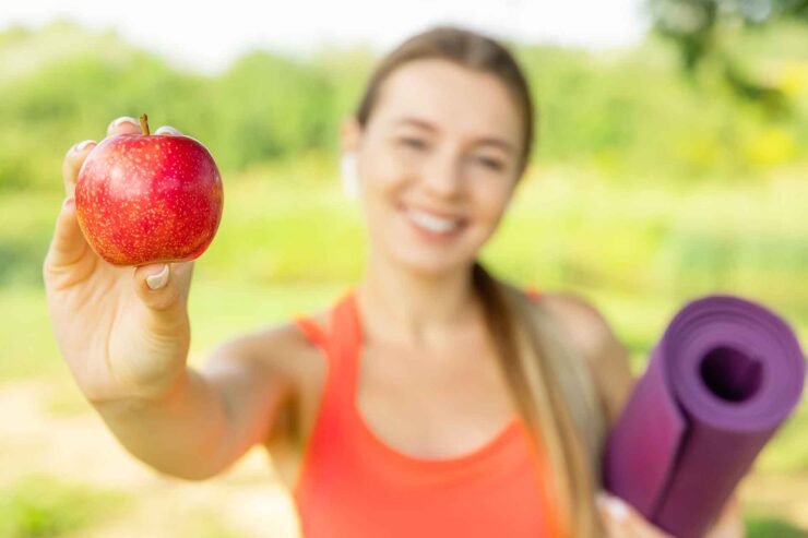 vrouw met apple en yogamat. Afvallen en Yoga: De Perfecte Combinatie